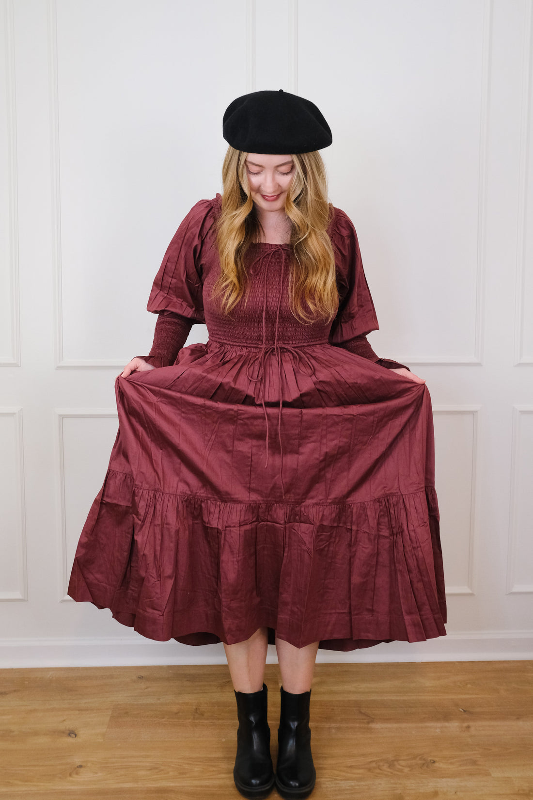 White woman in mulberry colored long-sleeve maxi dress and black french beret