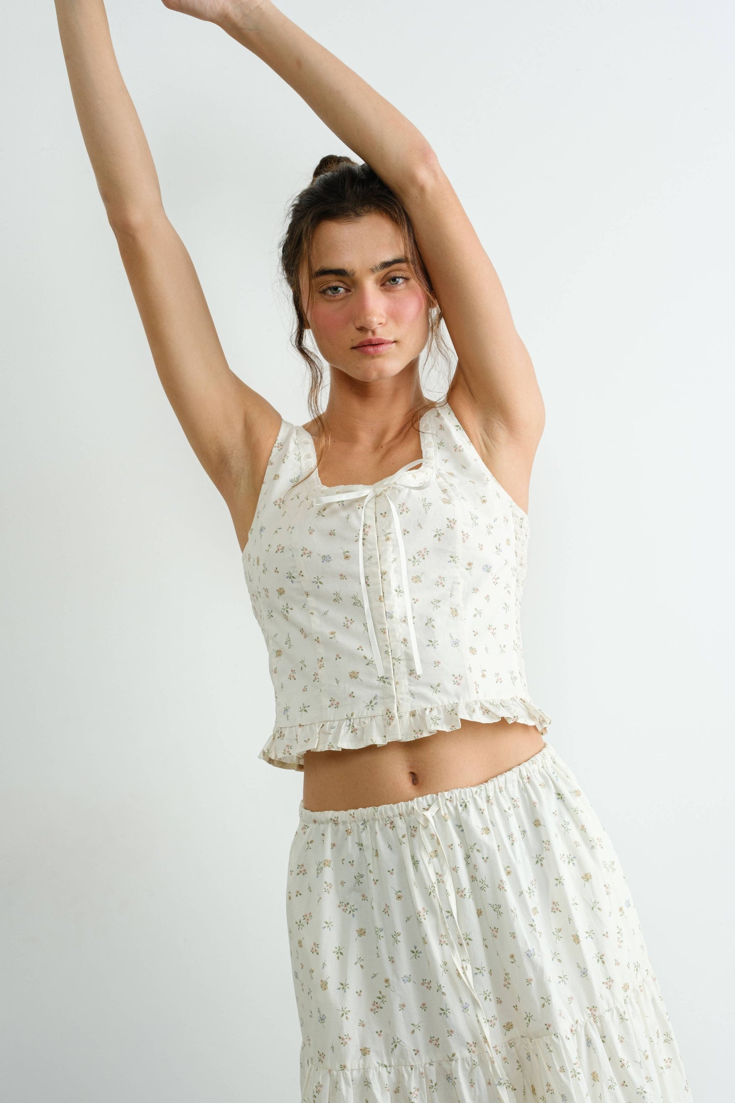 Woman wearing a white floral top and skirt against a plain background