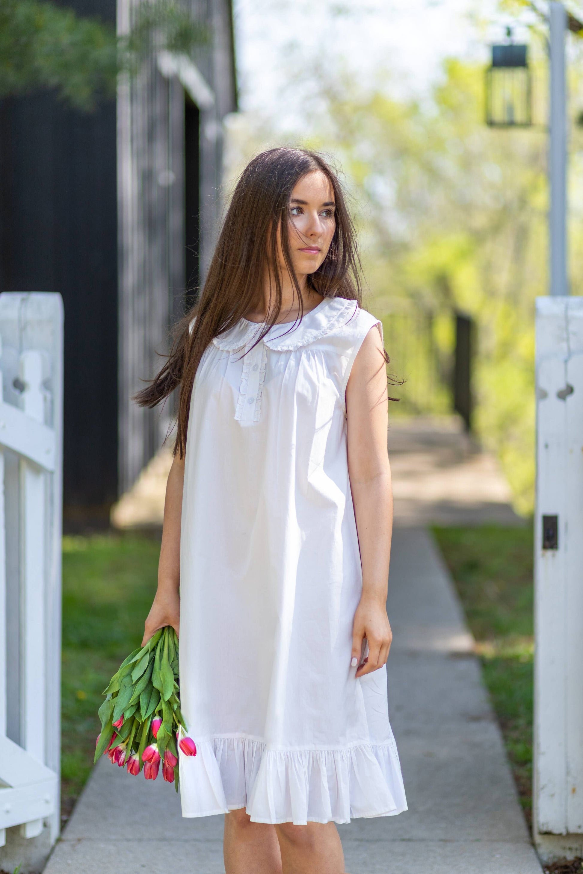 Woman in a white dress holding tulips on a sunny day.
