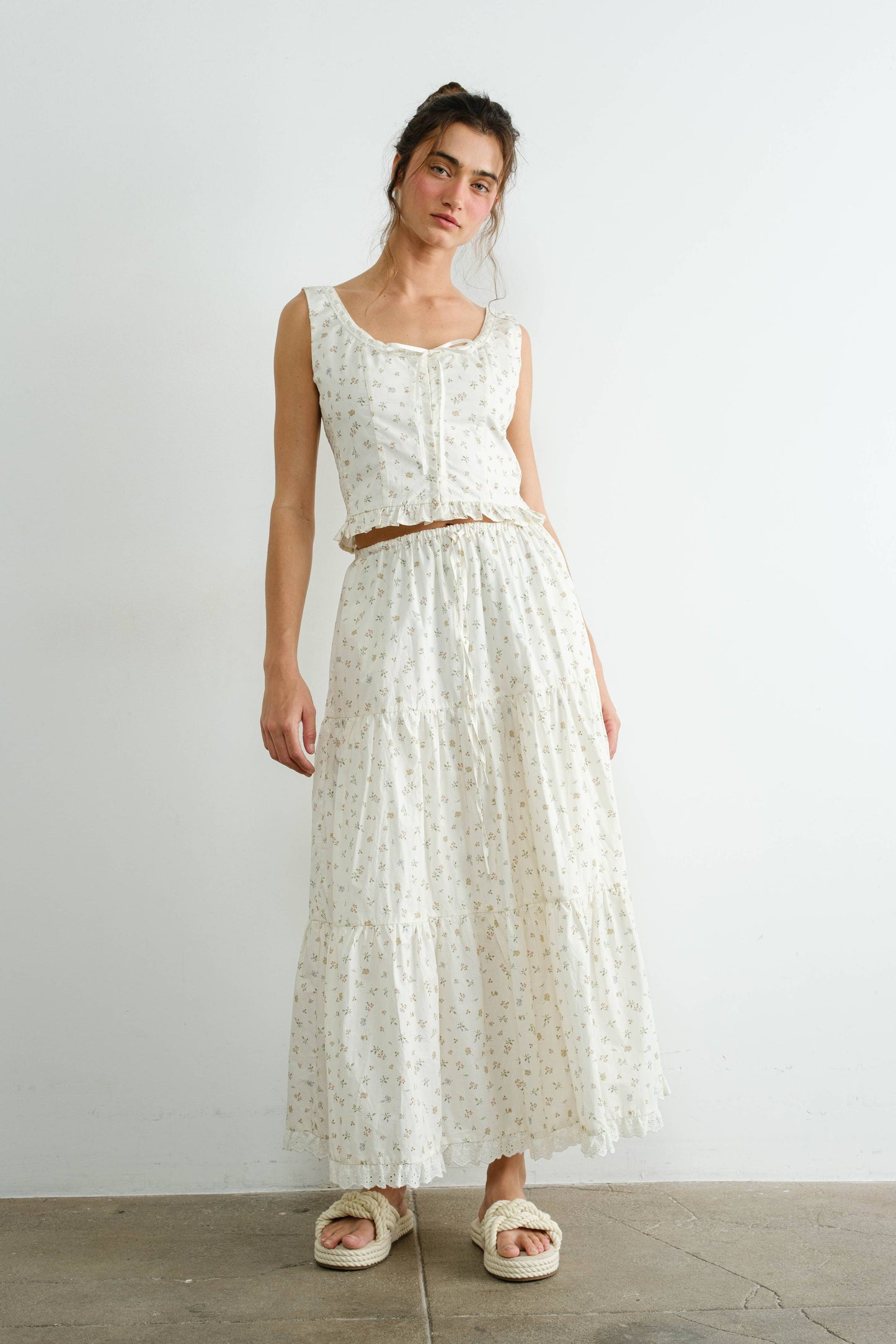 Woman wearing a white floral dress against a plain background