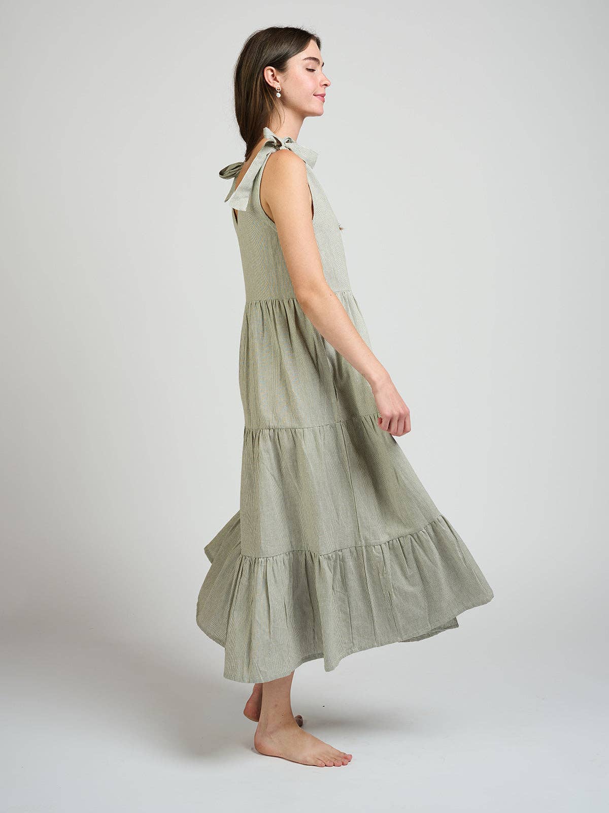 Woman wearing a light green dress with ruffled layers on a white background