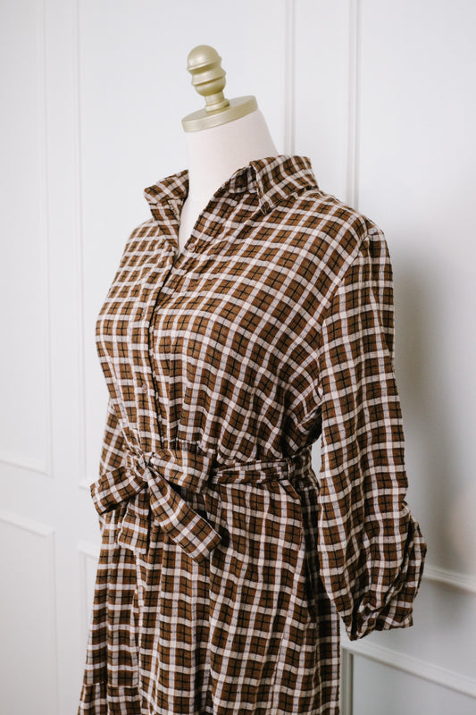Check pattern brown and ivory cotton shirt dress on a mannequin in front of a white wall