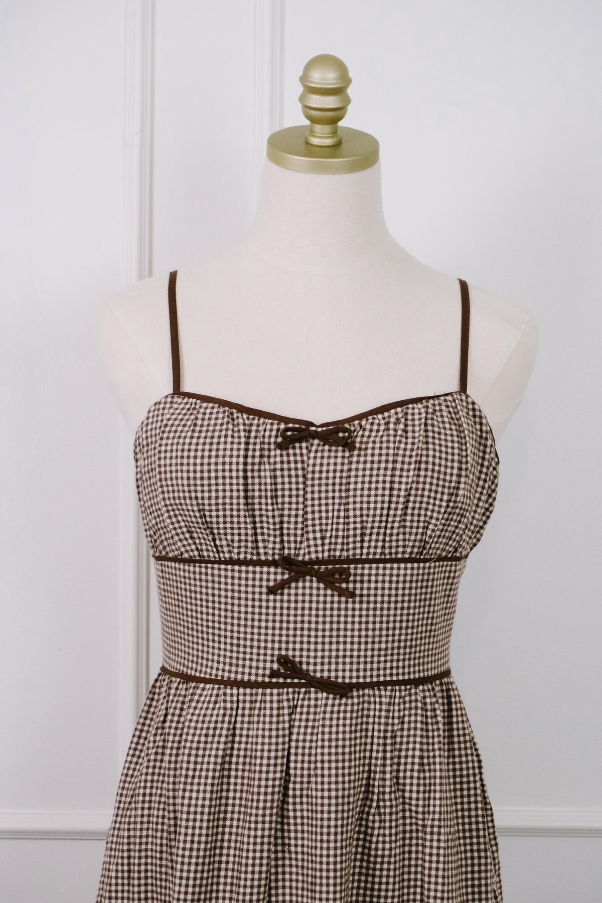 A brown gingham cotton dress with 3 brown bows down the front