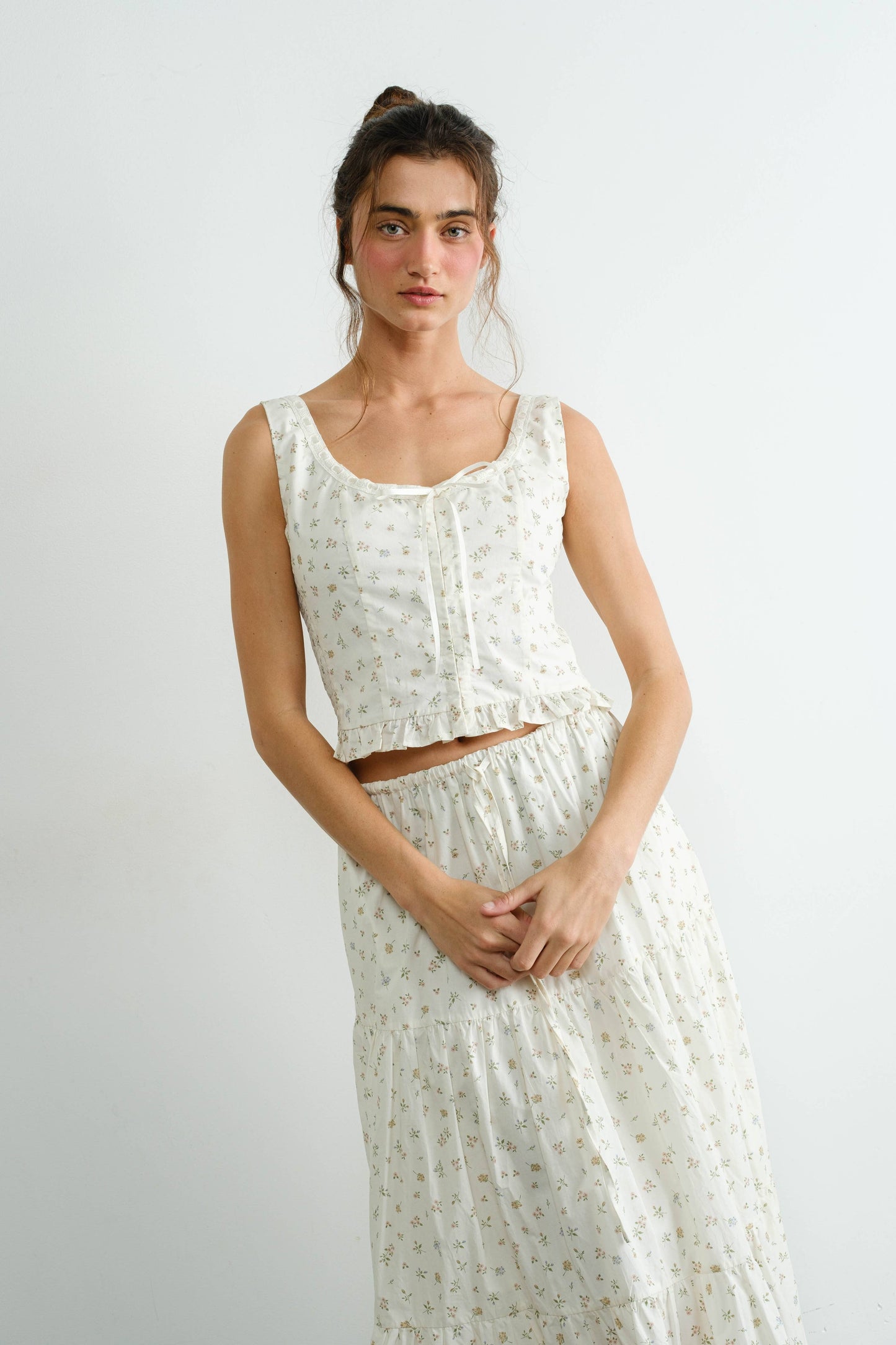 Woman wearing a white floral outfit against a plain background