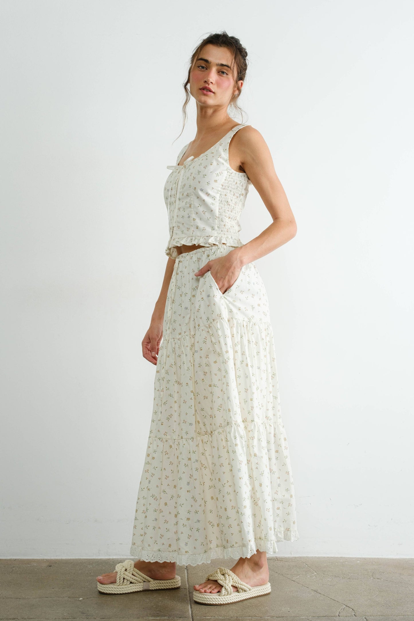 Woman wearing a white floral dress against a plain background