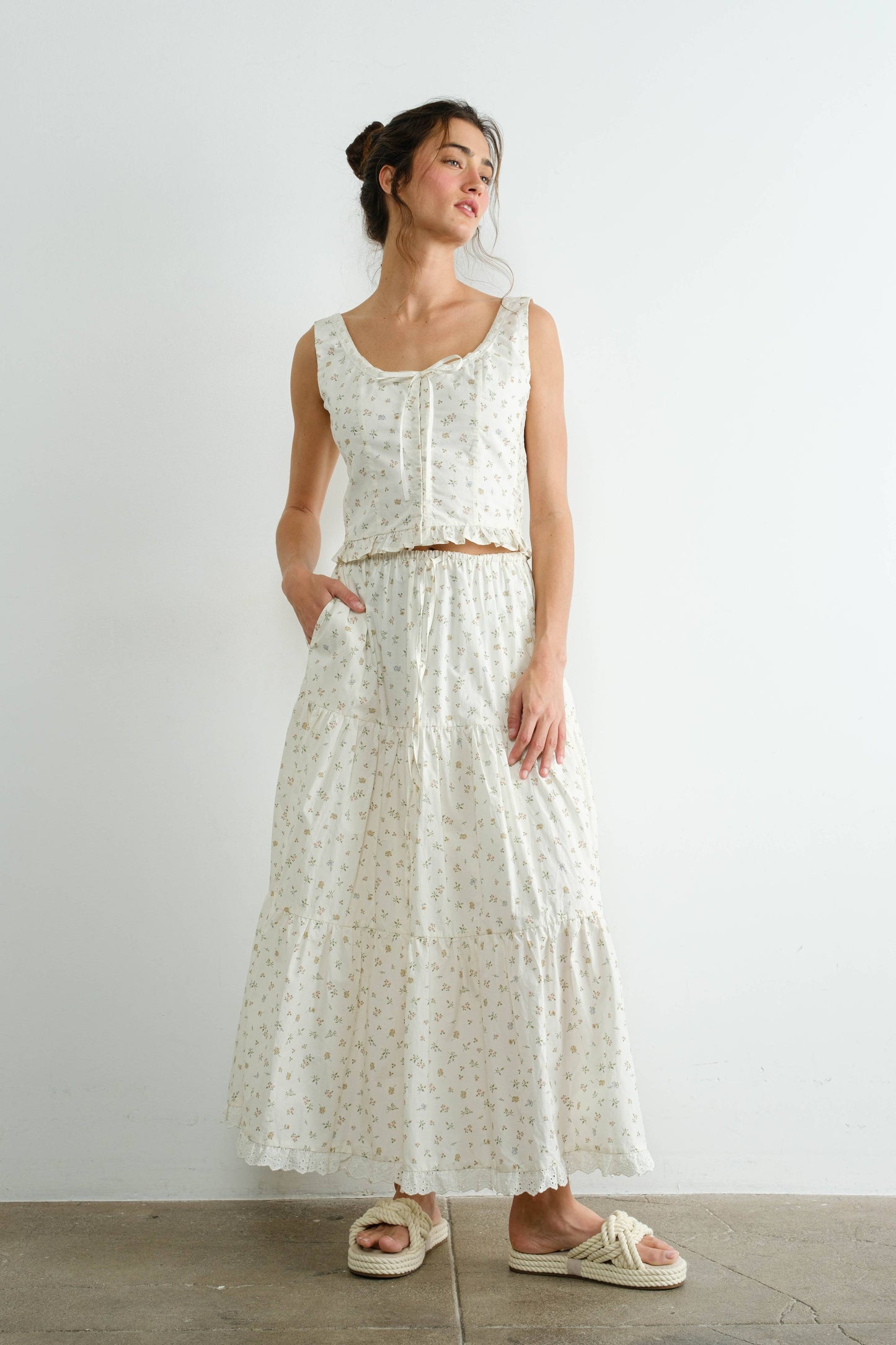 Woman wearing a white floral dress against a plain background