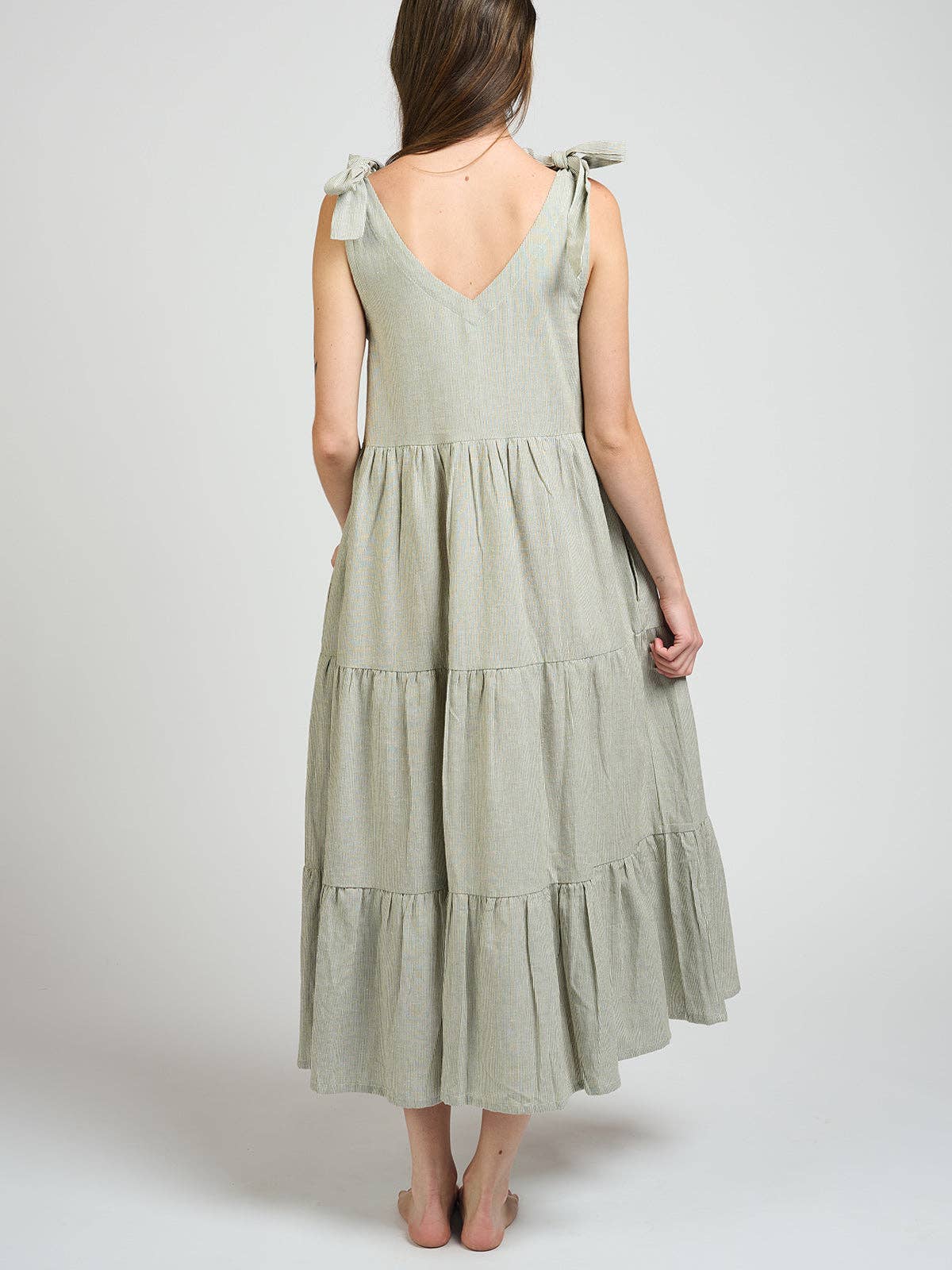 Woman wearing a light green dress with tiered skirt on a white background