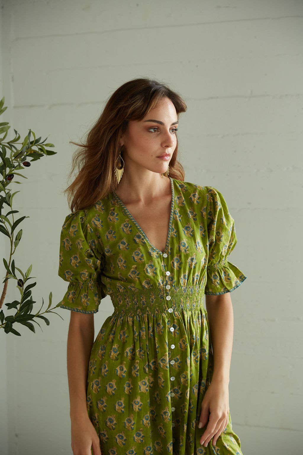 Woman wearing a green floral dress against a white wall